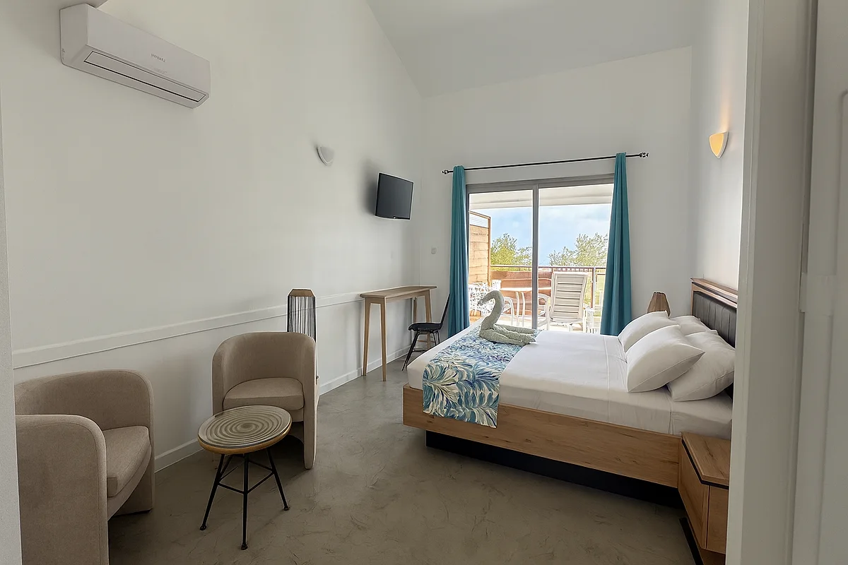 Un studio vue mer de L'Ilot Bleu : le lit, les fauteuils et la baie vitrée ouverte sur la terrasse