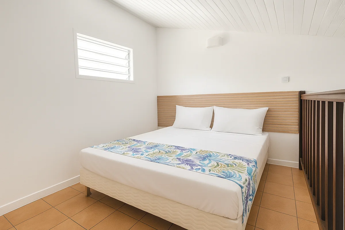 La chambre à l'étage d'un duplex, lit double sous la fenêtre