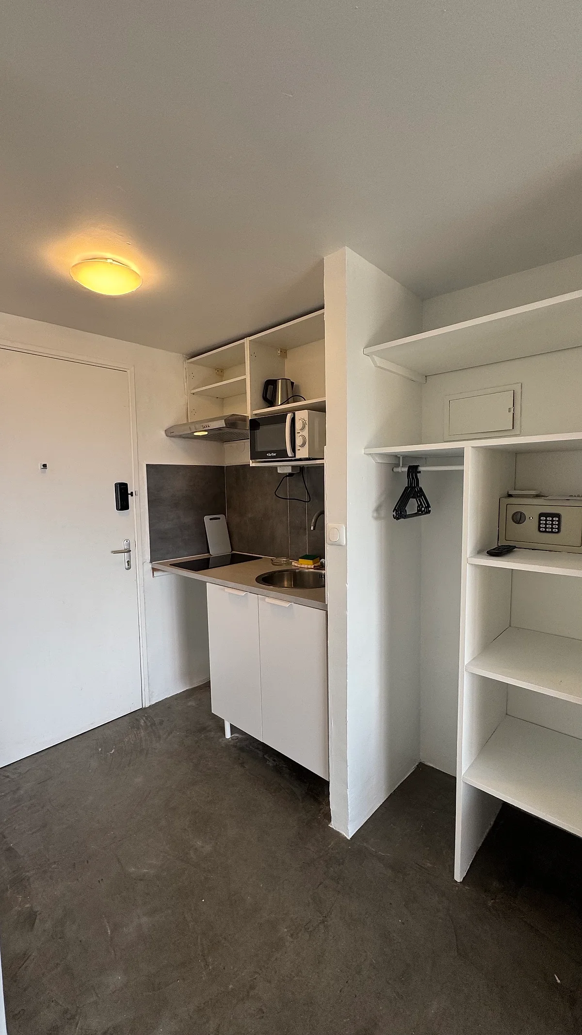 La kitchenette d'un studio, avec plaques, micro-ondes et coffre-fort